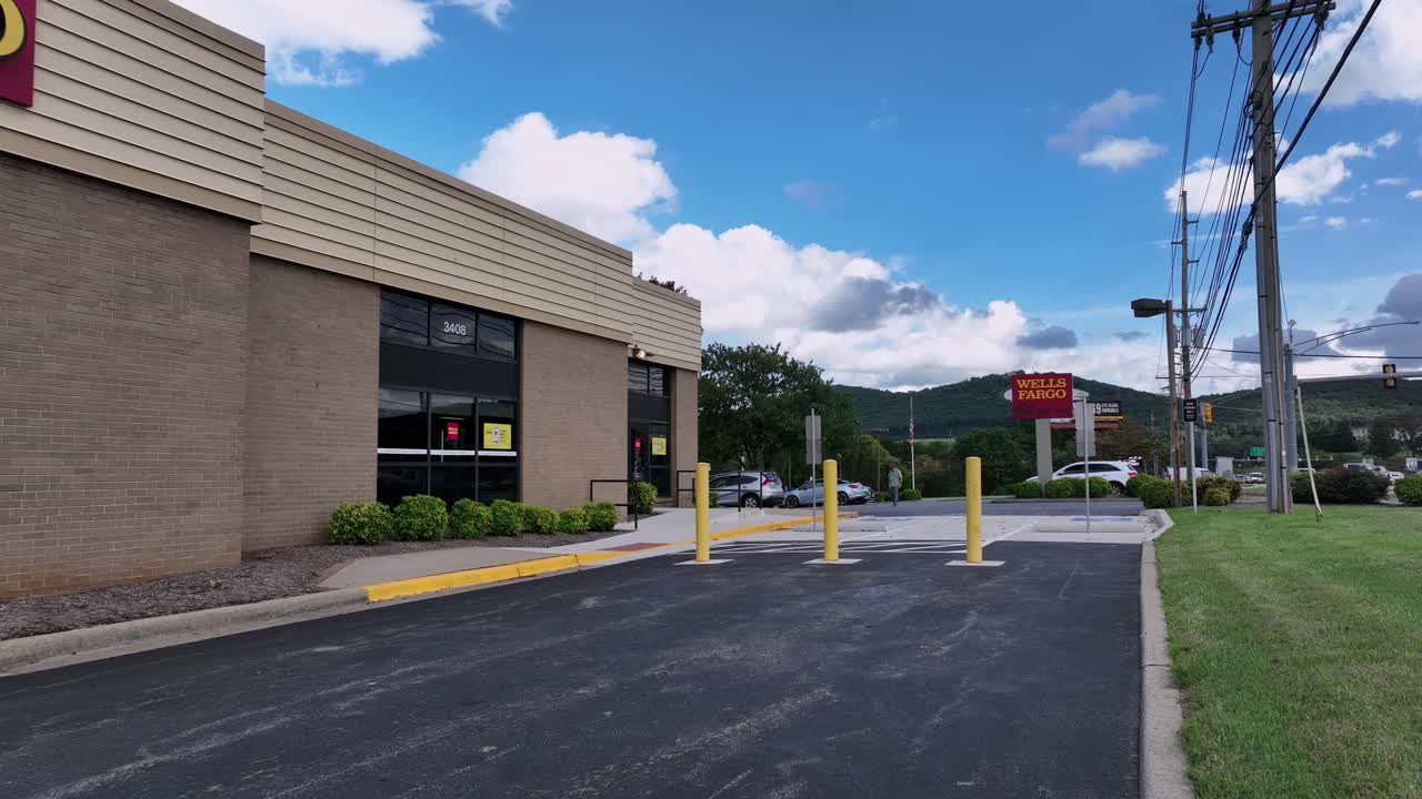 Welle Fargo Bank Building along American highway in Virginia. Aerial low angle flight. Man walking from parking area to store. Daytime in American suburb. River ridge mall in Lynchburg.