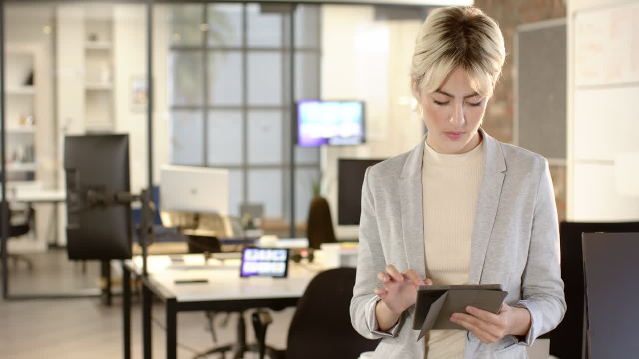 Using tablet, businesswoman working in modern office, focusing on tasks