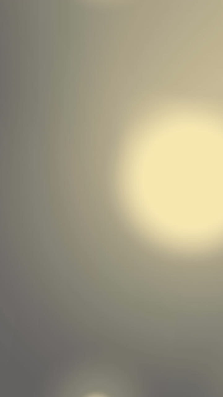 Animation of bokeh white light spots moving over grey background