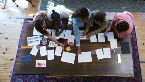 overhead view of team having creative design meeting around wooden table in office