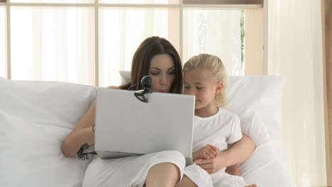 Mother-and-daughter-having-a-conference-call-in-bed