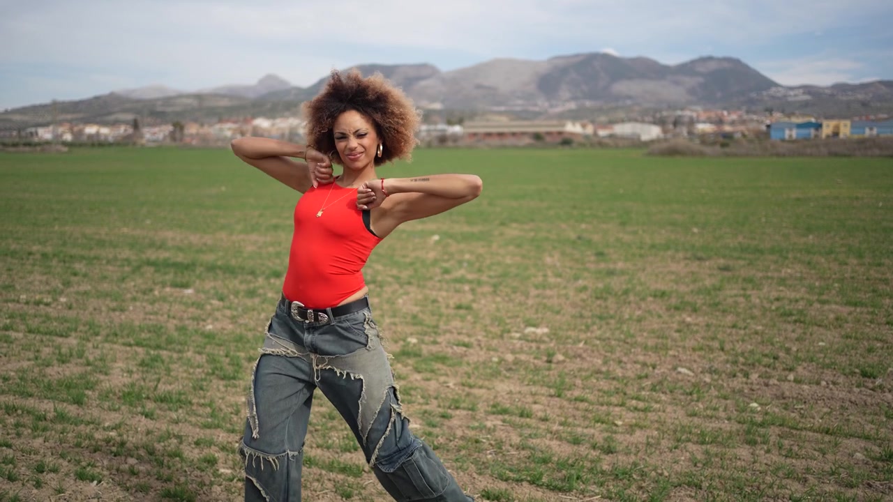 A woman in a colorful outfit poses confidently in a beautiful scenic field landscape
