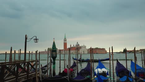 Venice-Italy-tourist-holiday-destination,-view-of-gondola-characteristics-boat-moored-at-gran-canal-in-san-marco-square-city-center,-with-san-Giorgio-church-in-background