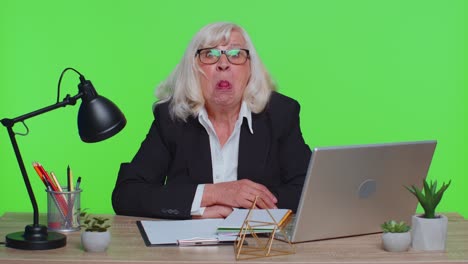senior mature older office businesswoman working on laptop computer making funny face fooling around