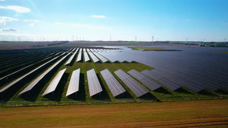 modern photovoltaic units producing green energy on farm field at sunlight - aerial flyover