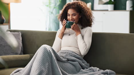 woman relaxing on the couch with a remote and a cup
