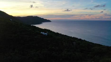 scenic aerial shot shows early morning light casting colorful hues across st. croix’s ocean and a forested peninsula, where the calm sea reflects the glowing sky above