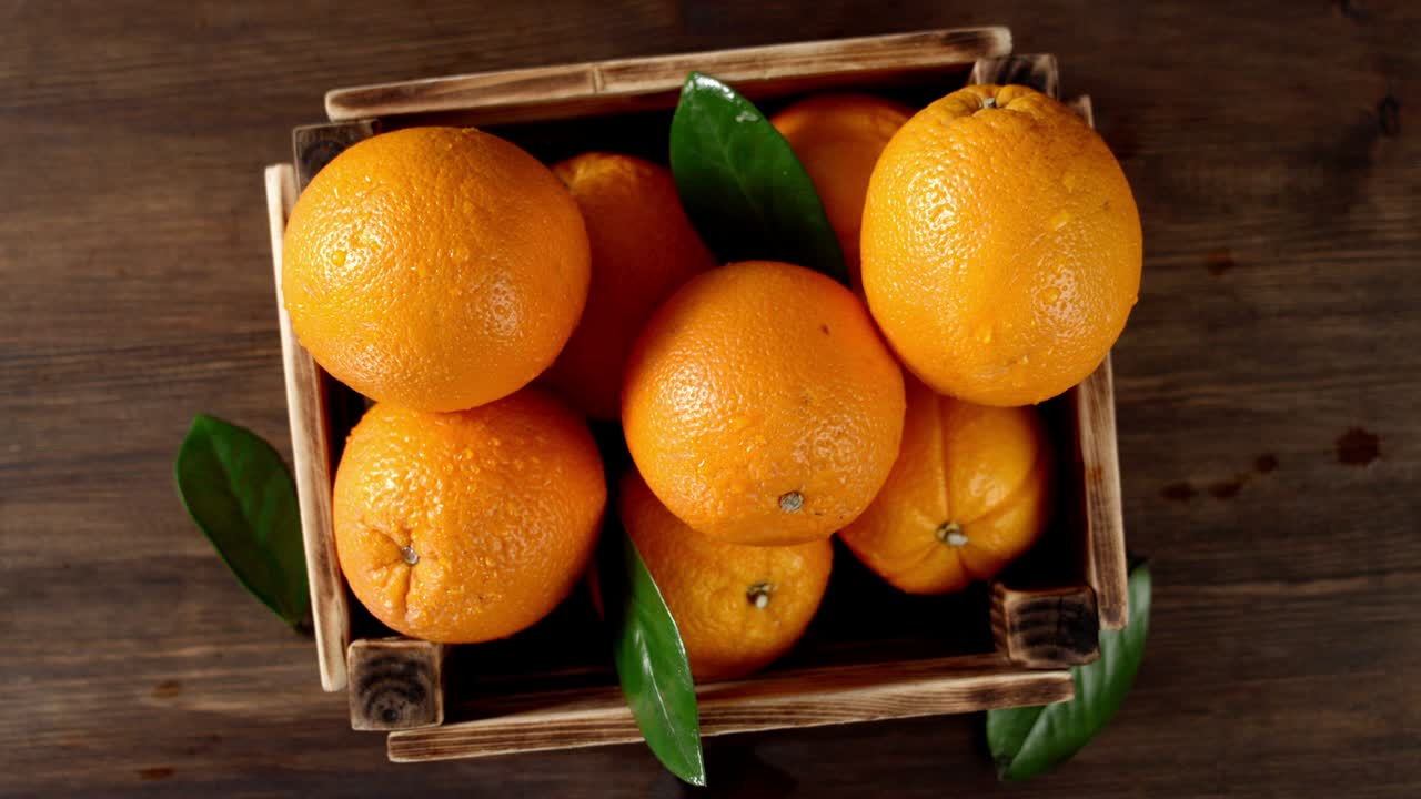 las manos de los hombres pusieron una caja de madera con naranja fresca en la mesa.