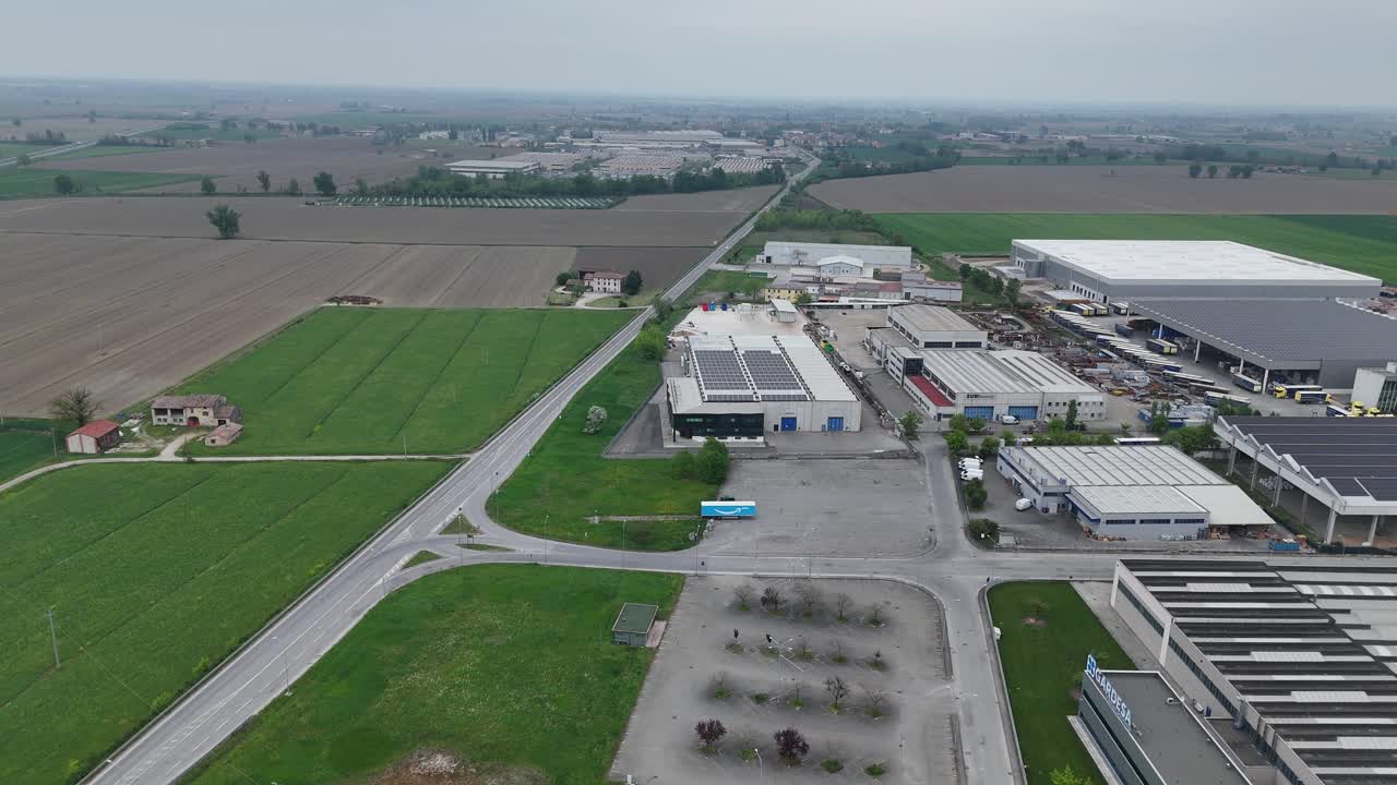 Zona industriale vicino a Cortemaggiore, Piacenza, Emilia Romagna, Italia, lungo la Via Emilia SS9 con magazzini e strutture logistiche all'interno del paesaggio agricolo della Pianura Padana, ripresa con drone.