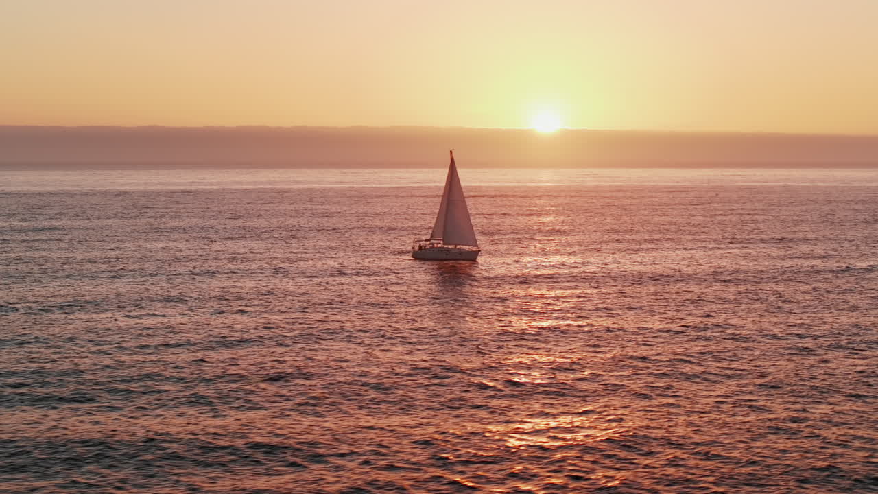 Aerial View of Sailboat Gliding Across Ocean at Sunset – Serene Golden Hour Maritime Scene - Drone - UHD