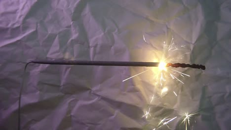 Close-Up-of-Fireworks-Light-Sparkler-Stick-and-a-Scratched-Paper-Background