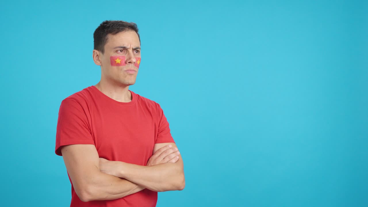 Mann mit aufgemalter vietnamesischer Flagge, der mit ernstem Gesichtsausdruck wegschaut
