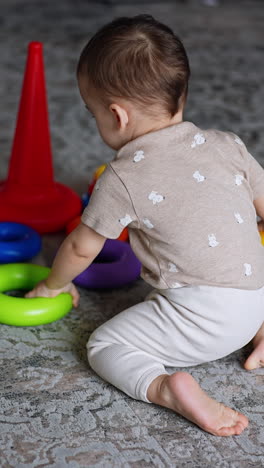 sweet little baby boy playing with toys on the floor. lovely toddler assembling pyramid and then crawls up the stairs. vertical video