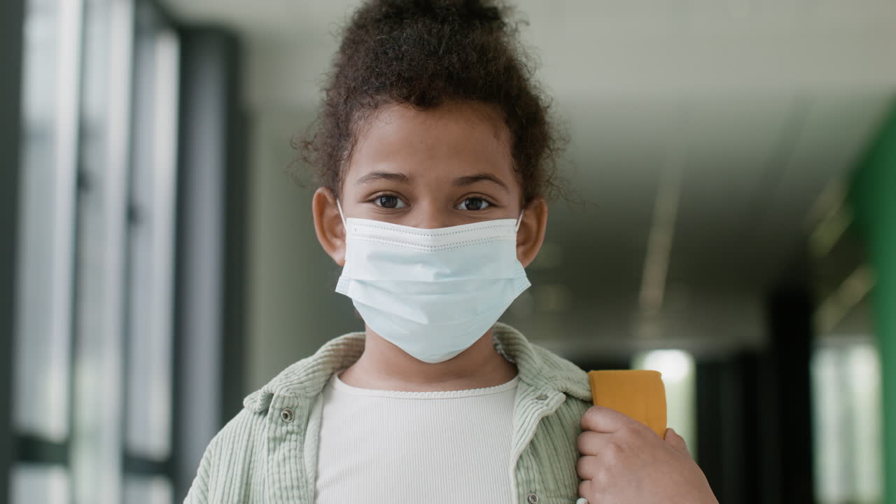 Schoolgirl with face mask in school corridor.