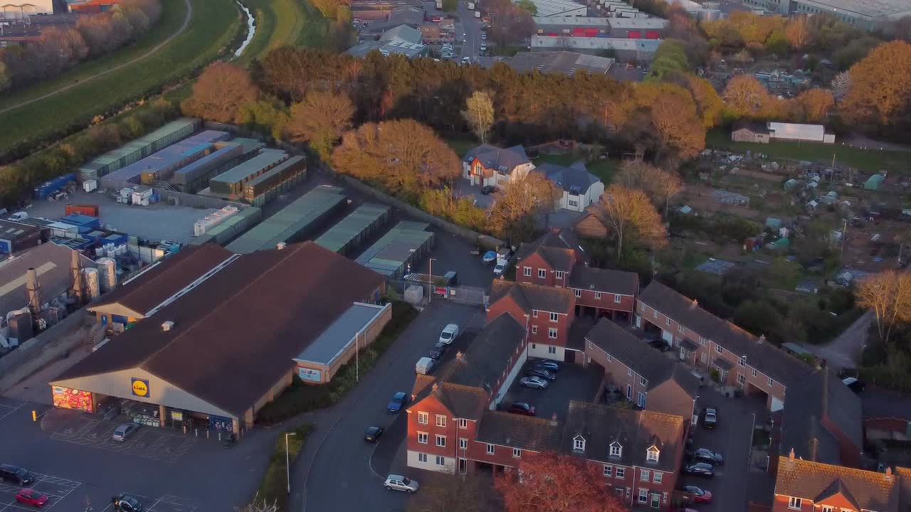 vista aérea de la hora dorada sobre el supermercado, las asignaciones y los suburbios en exeter, reino unido