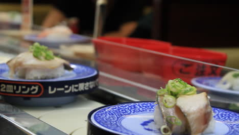 medium shot of conveyor belt sushi or rotation sushi or sushi train restaurant in osaka, japan