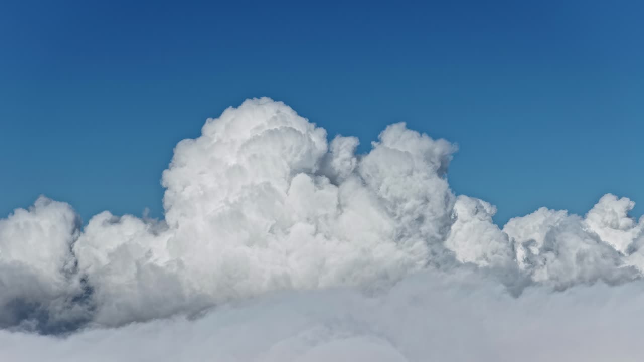 Timelapse lento di imponenti nuvole bianche che si ergono contro un cielo blu intenso, che mostra movimenti atmosferici intensi e mutevoli condizioni meteorologiche