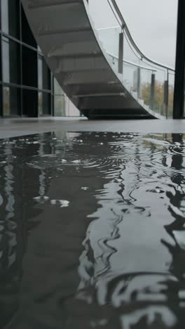 rippling puddle reflecting a modern staircase