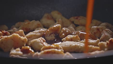 adding honey garlic sauce to chicken breast fillet cooking in a pan