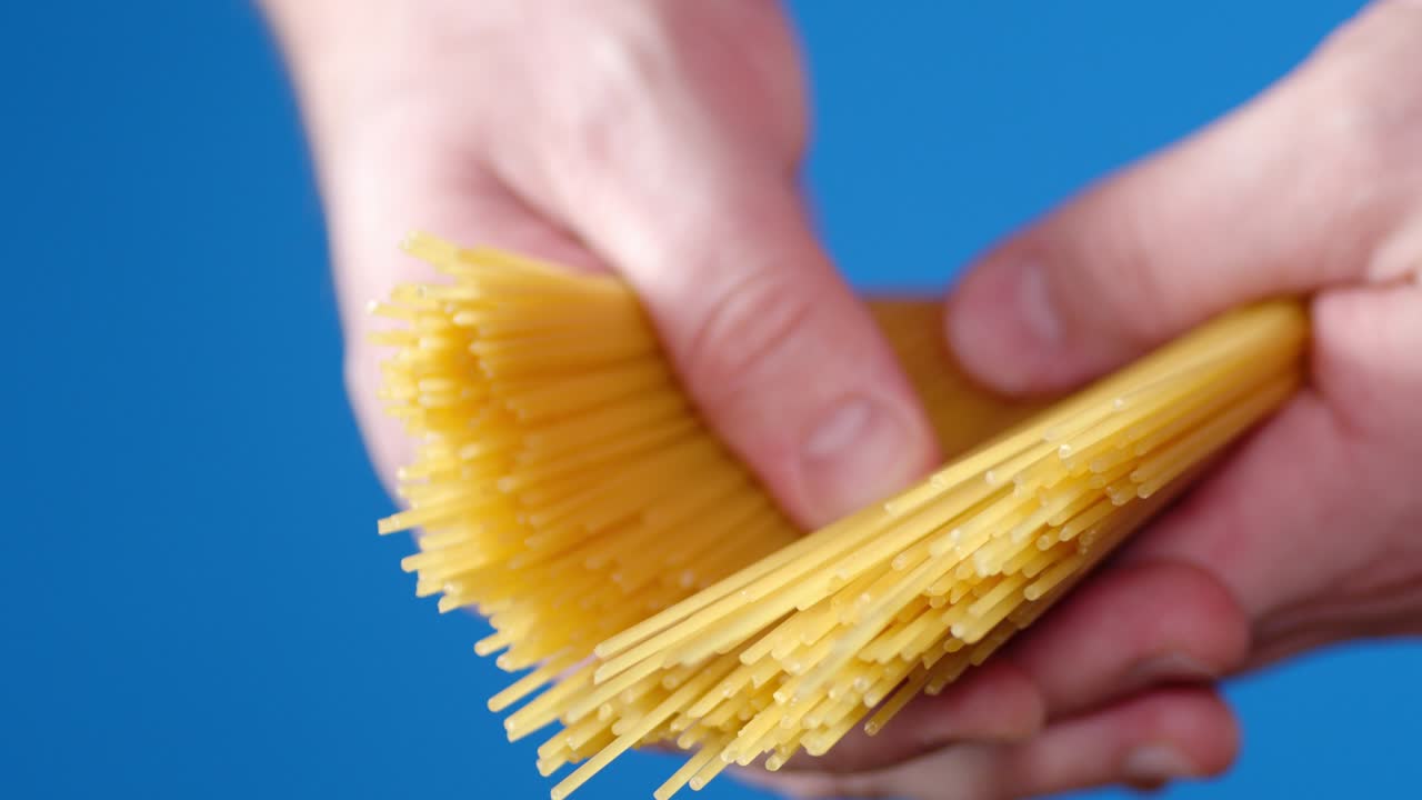 남자의 손은 건조한 파스타 스파게티 한 어리를 들고 있습니다.