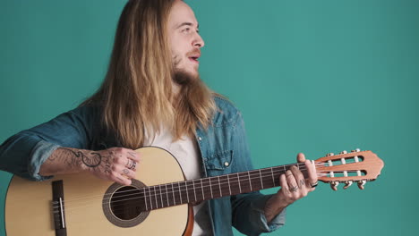 Caucasian-young-man-playing-guitar-and-singing-on-camera.