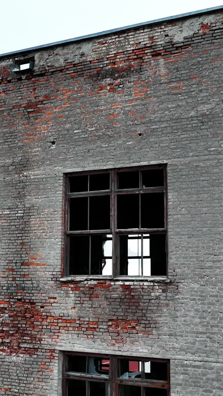 Old brick factory building. Coming closer to the house with broken windows, empty inside. Blue sky backdrop. Vertical video