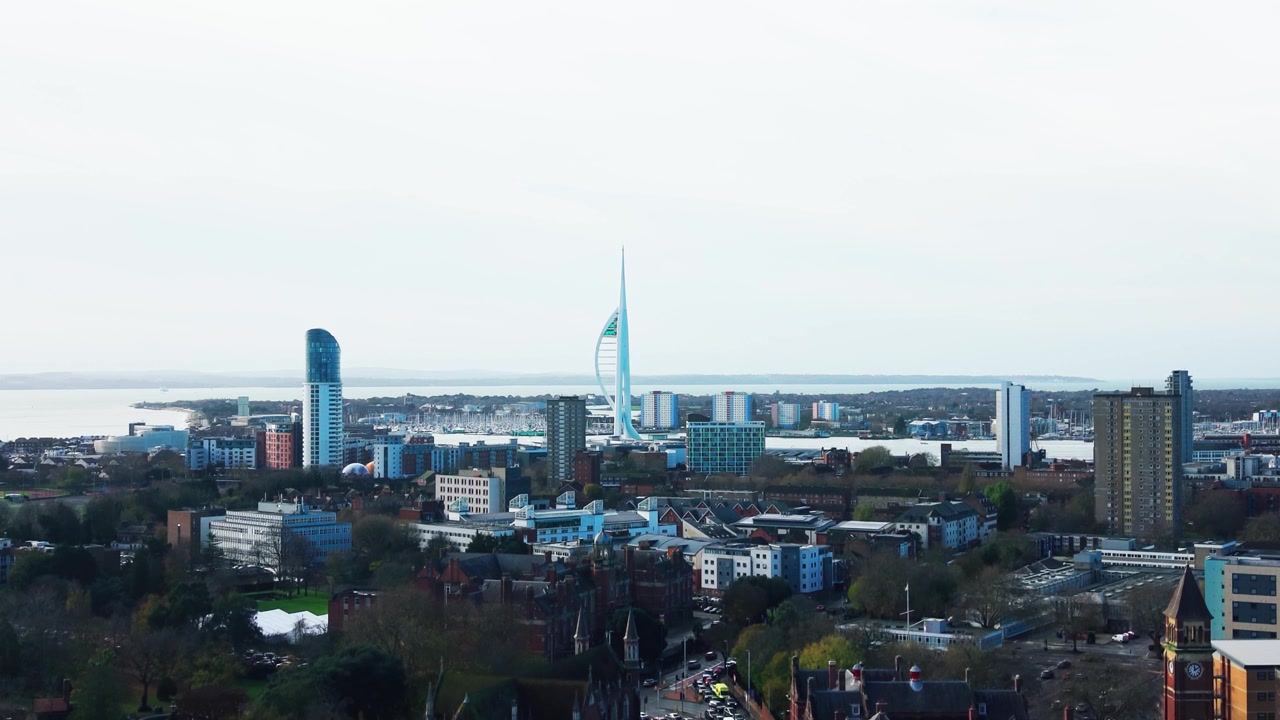Riprese aeree con drone dello skyline di Portsmouth di giorno, con la Spinnaker Tower, le acque del porto, le strade della città e il traffico di passaggio.