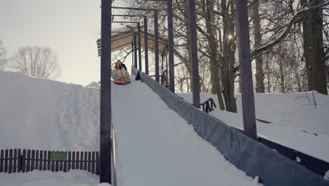 woman snow tubing down a snow hill