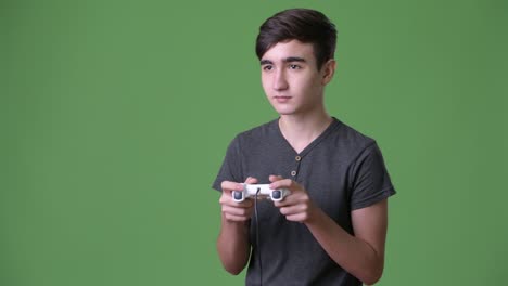 young handsome iranian teenage boy against green background