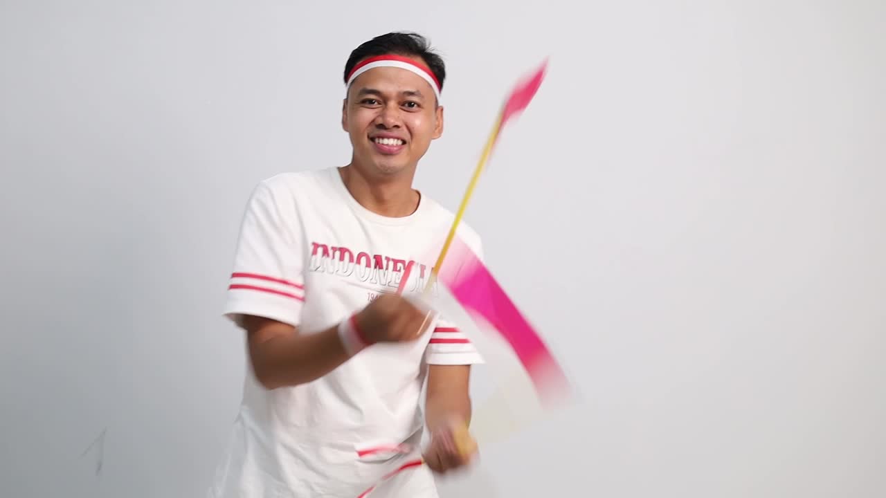 Cheerful Indonesian man standing holding red white flag to celebrates Indonesia independence day