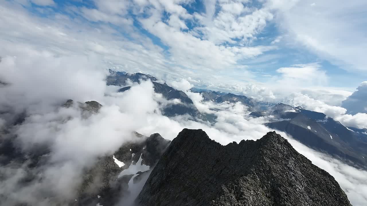 el dron fpv hace una atrevida caída por una ladera de la montaña por encima de las nubes, ofreciendo un emocionante descenso a través de vistas etéreas en gloria cinematográfica