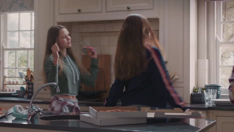 happy group of teenage girls dancing in kitchen eating pizza having fun celebrating together enjoying hanging out together on party weekend