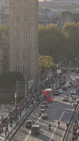 traffic and people crossing westminster bridge next to the houses of parliament, london, uk in vertical