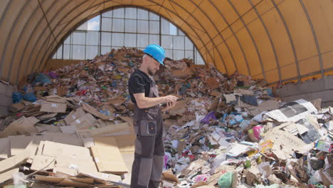 Trabajador-Con-Overoles-Haciendo-Notas-Sobre-La-Basura-De-Papel-Reciclado-En-Las-Instalaciones,-Perfil