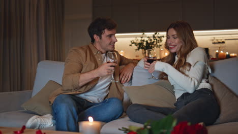 family couple enjoy romantic leisure with wine on couch. man giving wineglass