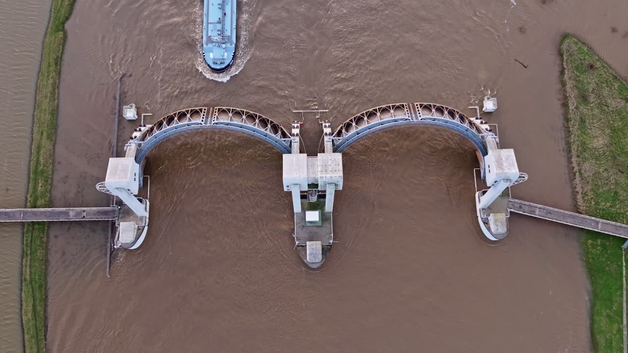 Top down drone shot of the weir of Driel with a cargo ship passing thru the wier during high water levels