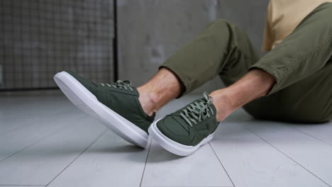 man sitting in olive green pants with green sneakers