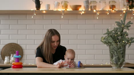 mother and baby are looking to play and read tablet computer on the couch at home