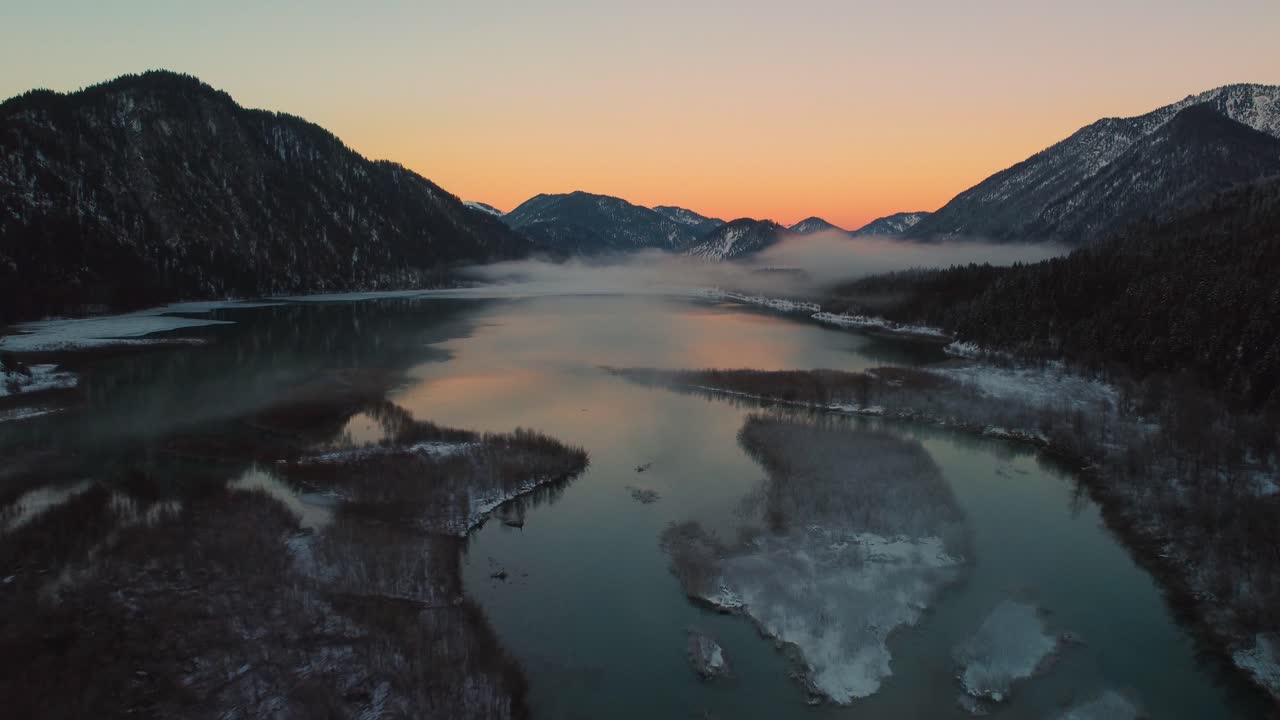 Beautiful Bavarian Austrian alps mountain river valley with fresh water at Sylvensteinspeicher by sunshine sunset, winter snow riverbed, trees and forest and mountains