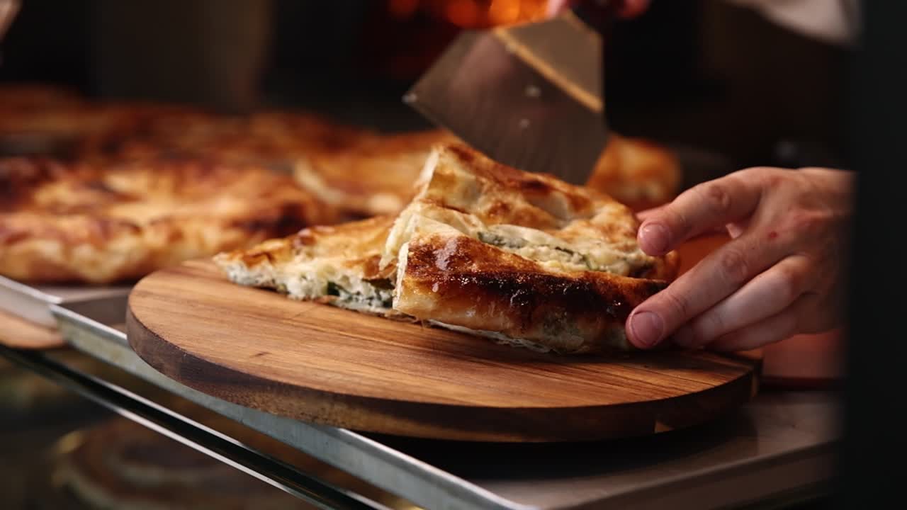 Chef che affetta un prodotto da forno salato appena sfornato su un tagliere di legno