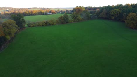 sideways drone shot of english field with church and rich countryside estate in background - aerial 4k