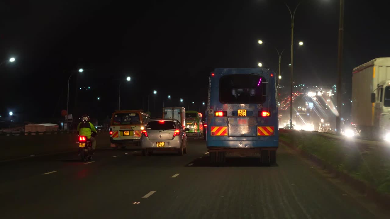 Heavy traffic on Nairobi Highway at night, vehicles with bright headlights on urban road