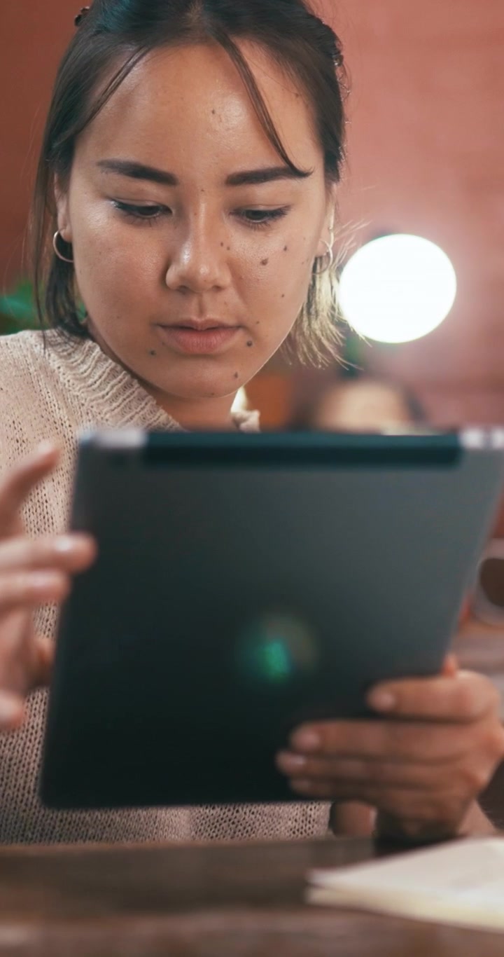 Ung kvinde bruger en tablet i hyggelige, indendørs omgivelser