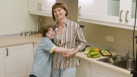 Feliz-Madre-E-Hija-Sonriendo-Y-Abrazándose-En-La-Cocina