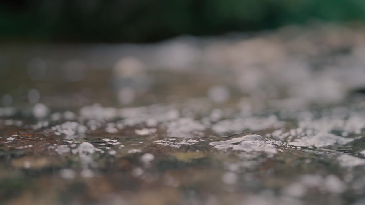 Primer plano de agua cristalina fluyendo sobre rocas en un arroyo