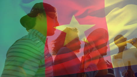 Friends holding drinks with Cameroon flag animation overlay in celebration mood