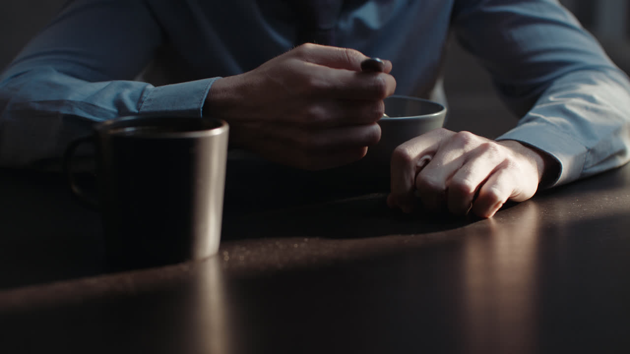 A sad man in a shirt slowly eats breakfast