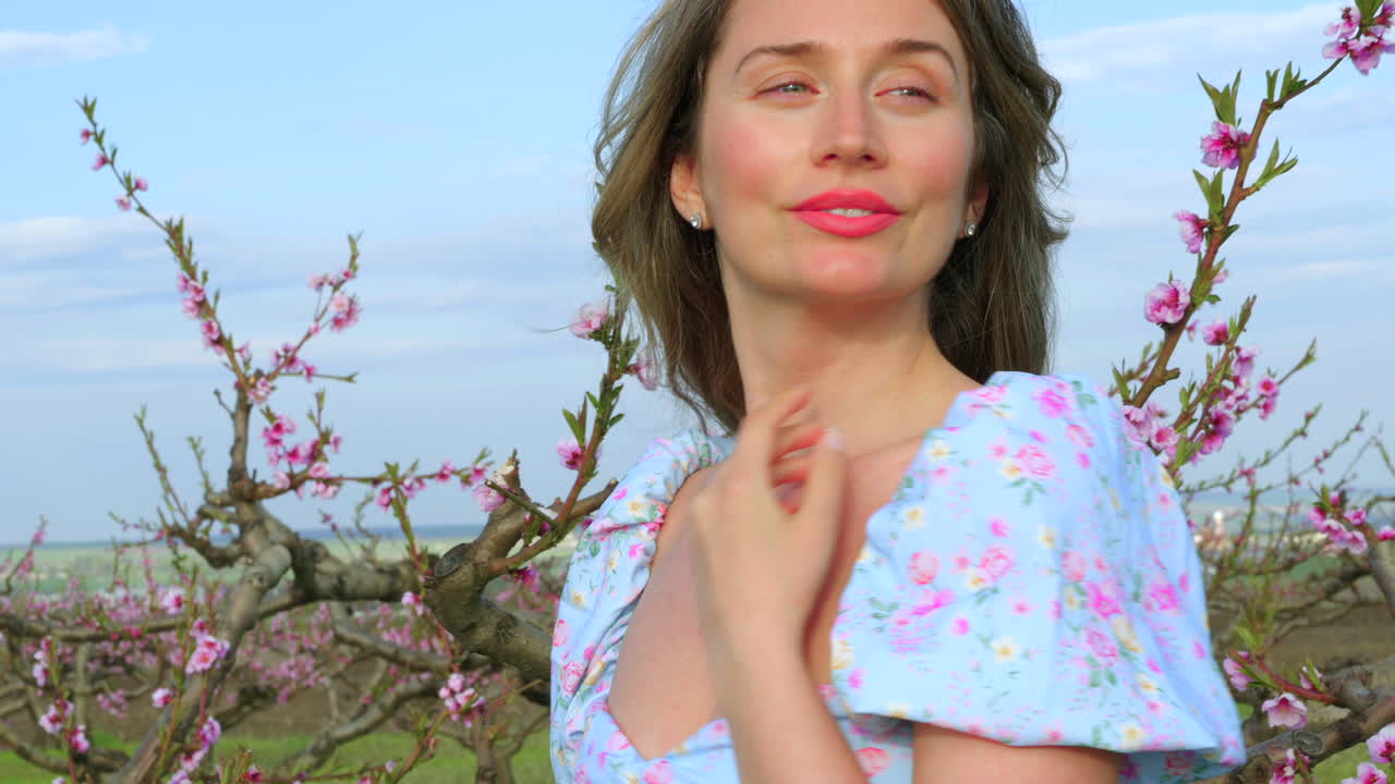 Brunette woman in a blue dress in a field of blooming trees