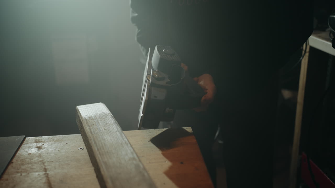 Clumsy woodworker trying to fix his misaligned planer by slamming it on the table in his workshop