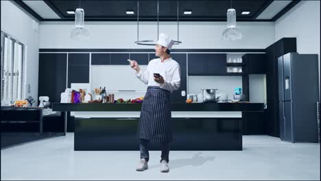 full body of asian man chef using smartphone and pointing to side while standing in home kitchen